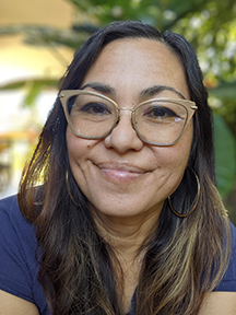 Sandra Fitzgerald smiling with long brown hair, glasses, and light brown skin