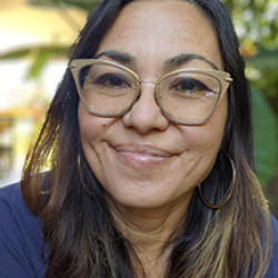 Sandra Fitzgerald smiling with long brown hair, glasses, and light brown skin